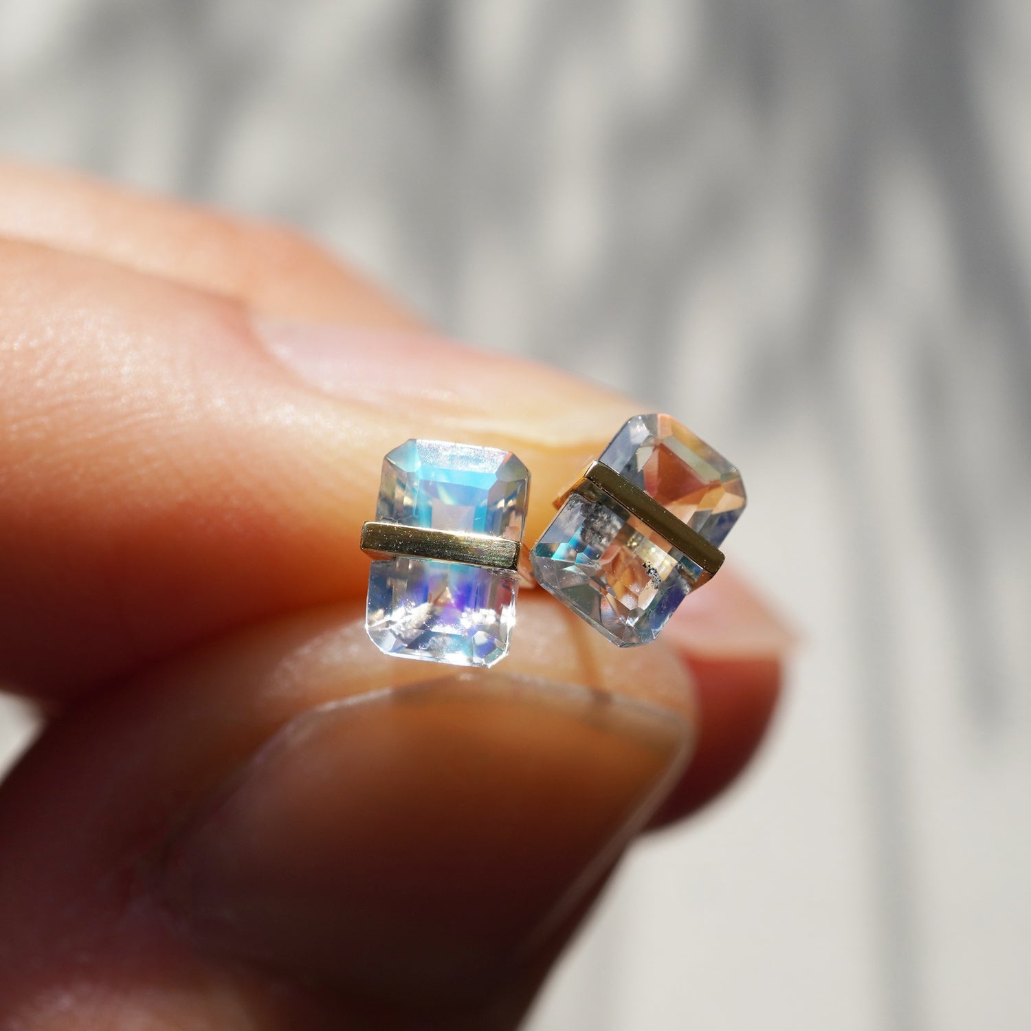 レインボームーンストーンの遊色と透明感が際立つピアスのクローズアップ。左右の違いも面白い