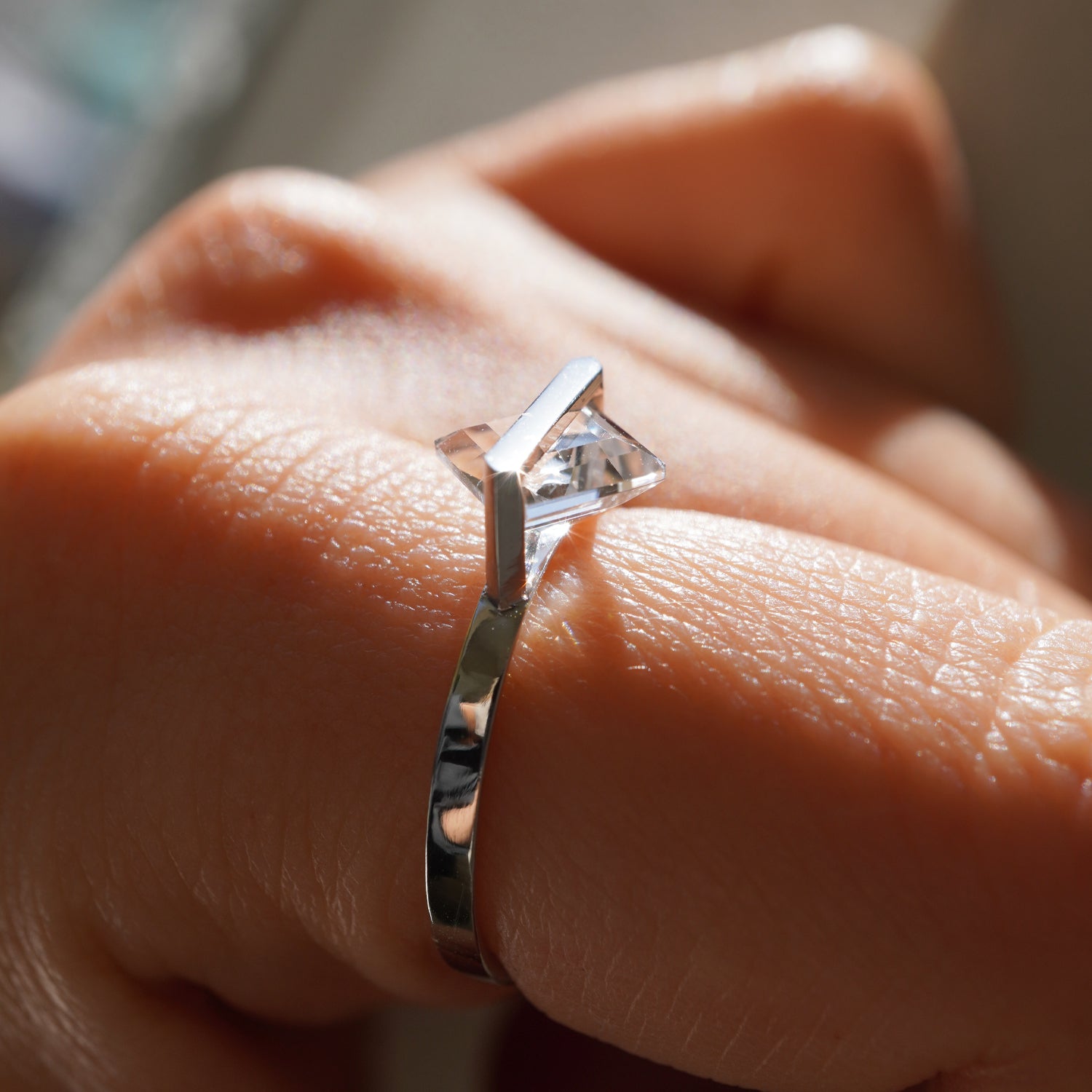 菱形カットのクオーツの透明感が際立つPt900リングの横から見たクローズアップの着用イメージ、バーで固定した構造(11号)