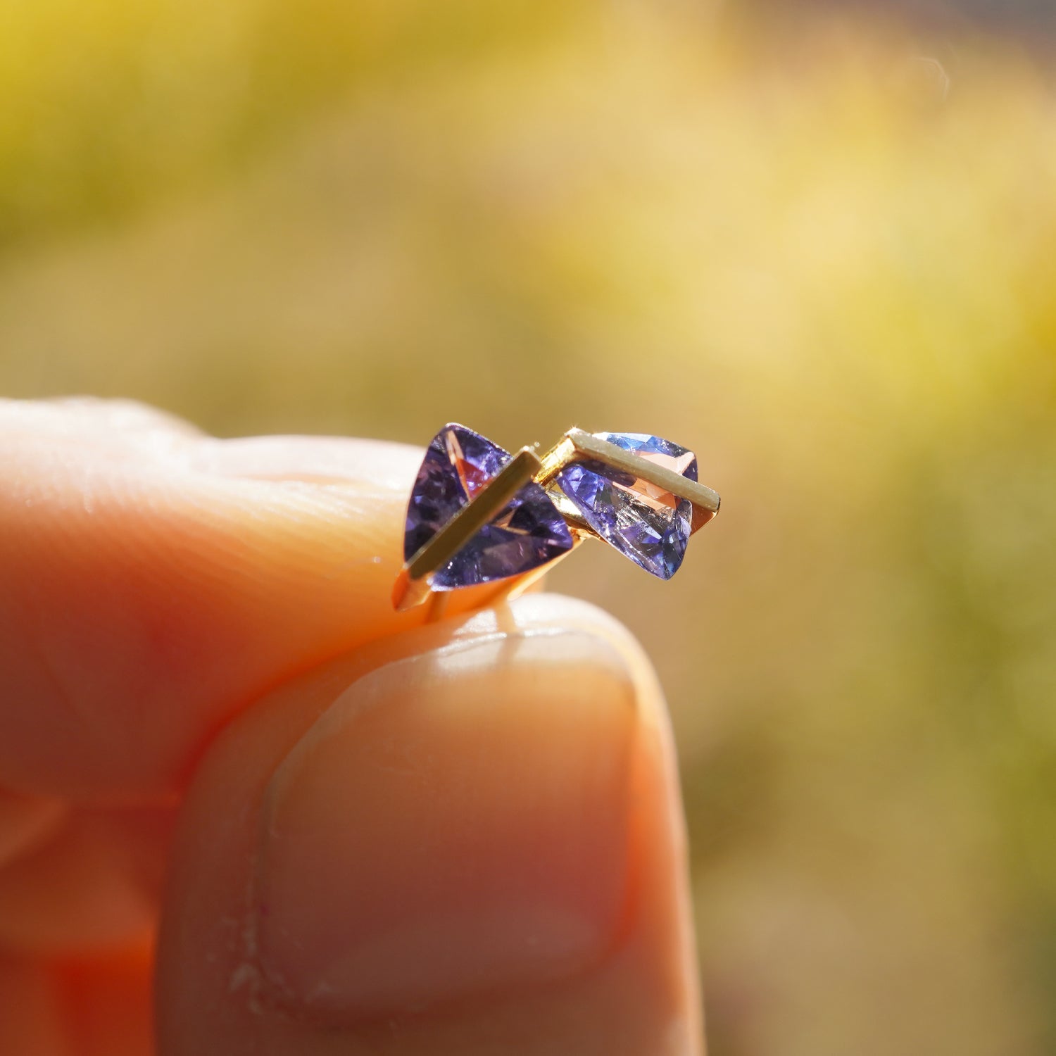 タンザナイトの青紫の色味とカット面が際立つK10イエローゴールドピアスのクローズアップ(ペア・ポストK18YG)