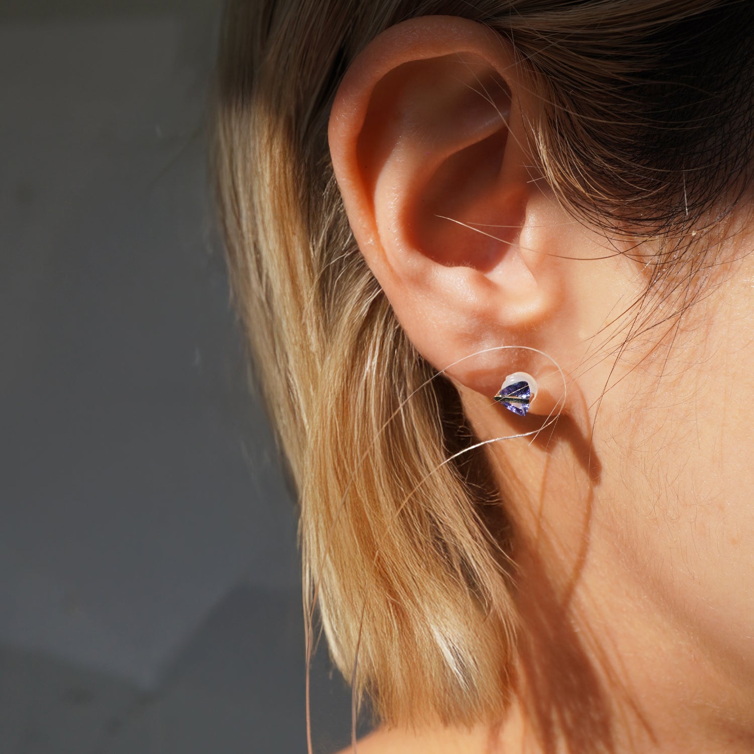 三角形のタンザナイトピアスの着用イメージ、ちょっと斜めから見た耳元でのサイズ感がわかるイメージ