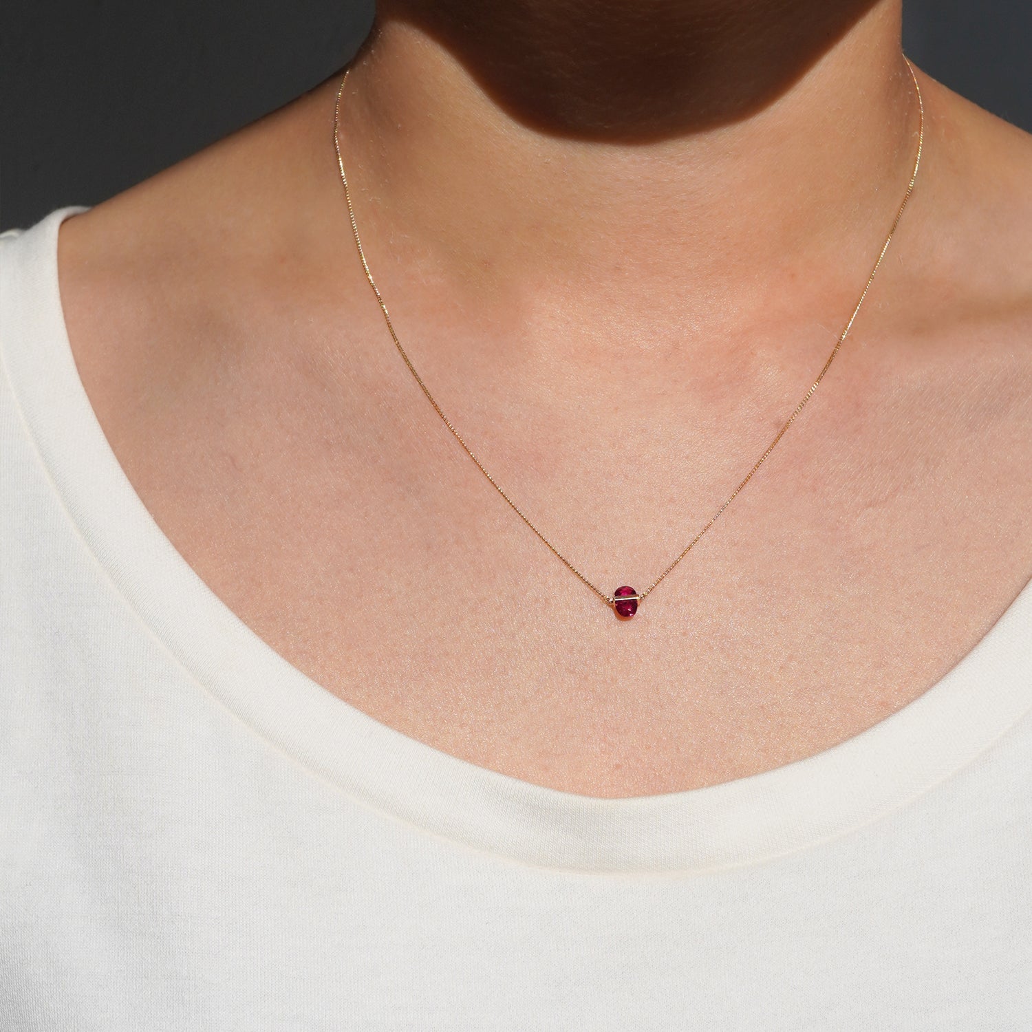 RUBY(ルビー)の天然石を横断するようにバーで固定したゴールド(K10YG)ネックレス、正面からの着用