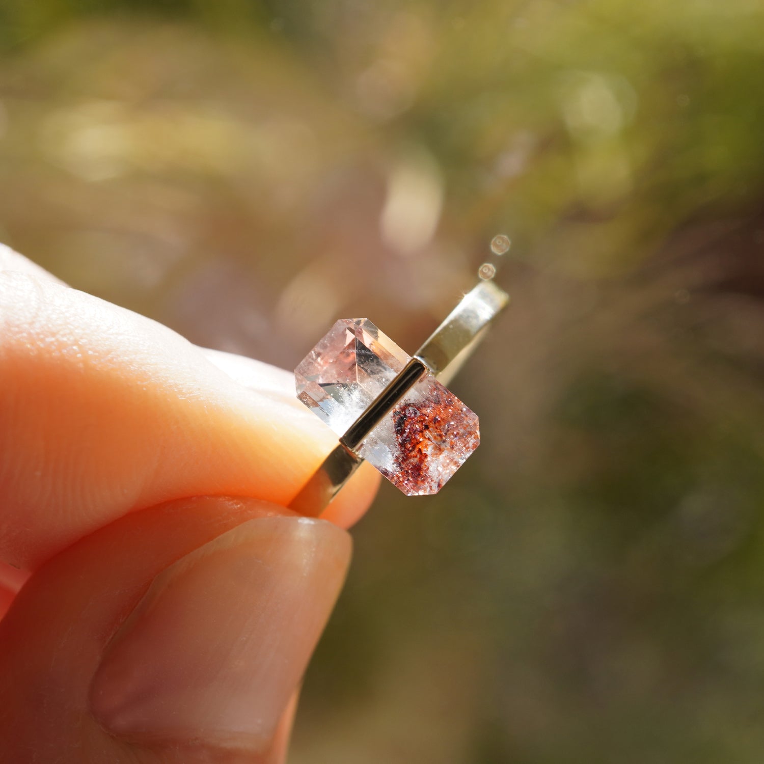 赤い内包物が見えるヘマタイトインクォーツの透明感が際立つK10イエローゴールドリング、手に持ったクローズアップ（11号）