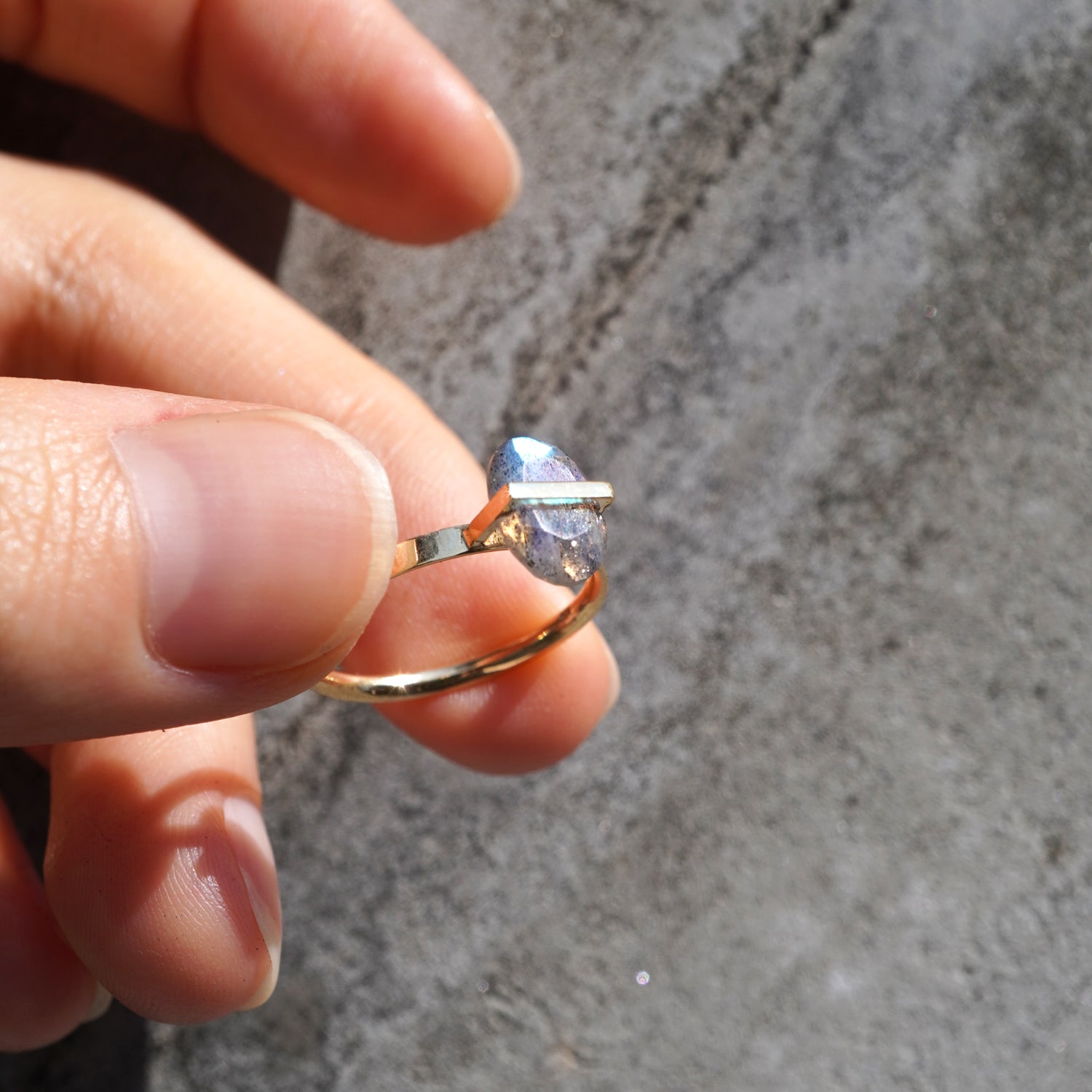 ラブラドライトを使用した指輪。自然光で指で摘んで斜めから見た写真。遊色効果も見れて美しいラブラドライト。
