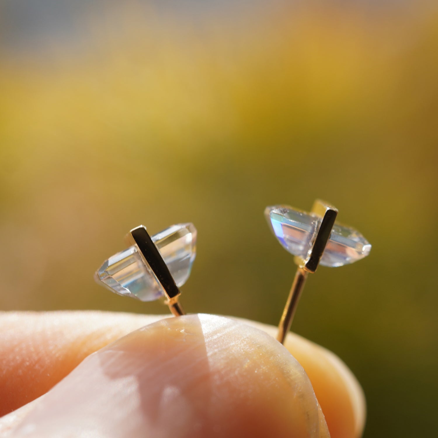 レインボームーンストーンの遊色と透明感が際立つピアスのサイドから見たクローズアップ（バケットカット・ペア）