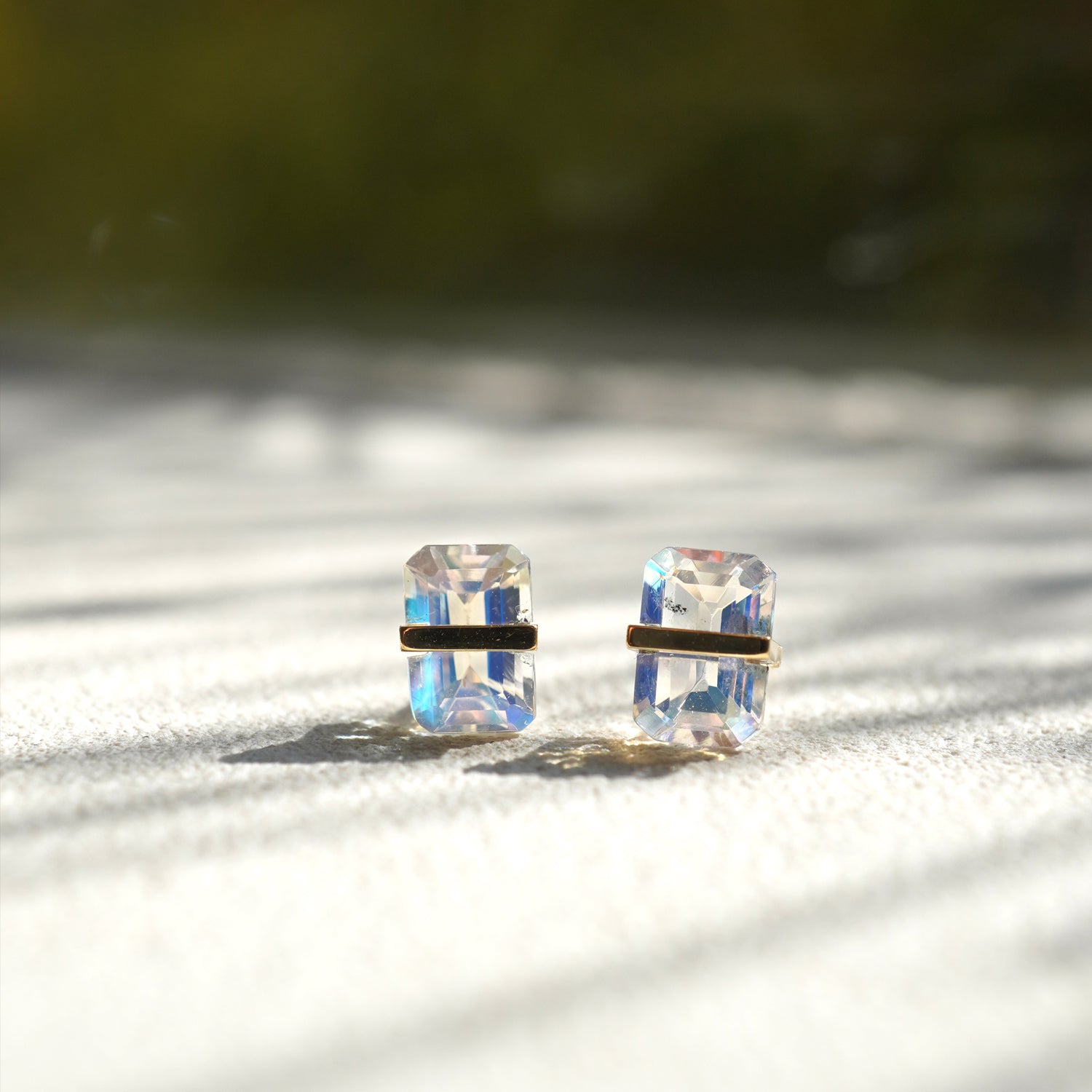 バケットカットのレインボームーンストーンをセットしたピアス（ペア）、青や虹色の遊色が特徴の石です。