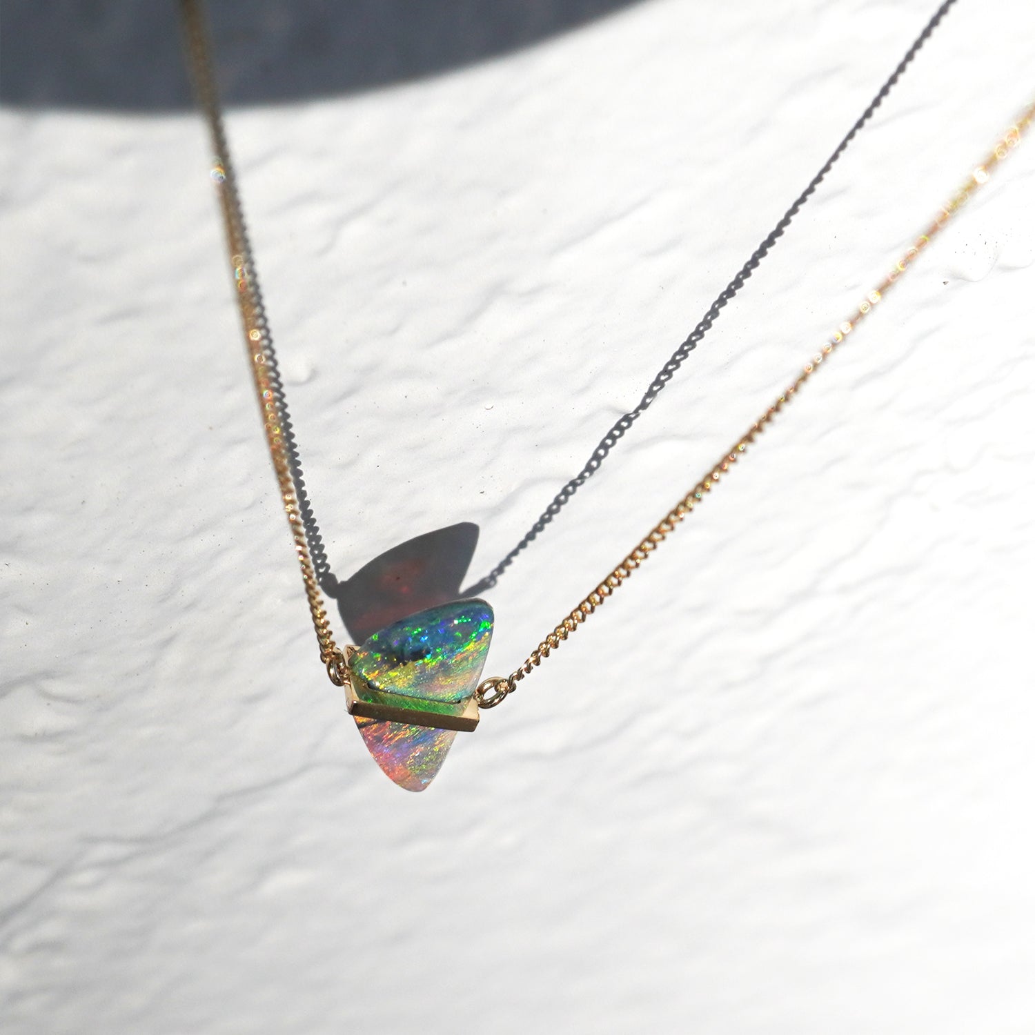 ボルダーオパールの遊色と石どめの構造がわかるK10イエローゴールドネックレスの上から見たクローズアップ