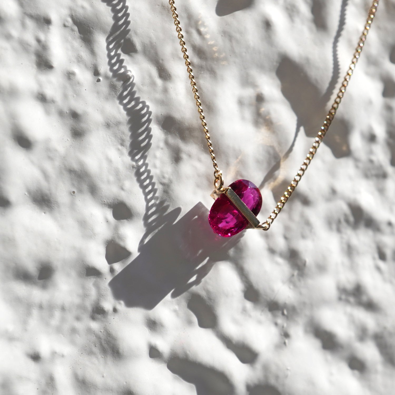 RUBY(ルビー)の天然石を横断するようにバーで固定したゴールド(K10YG)ネックレス、構造を見せるミニマルなデザイン