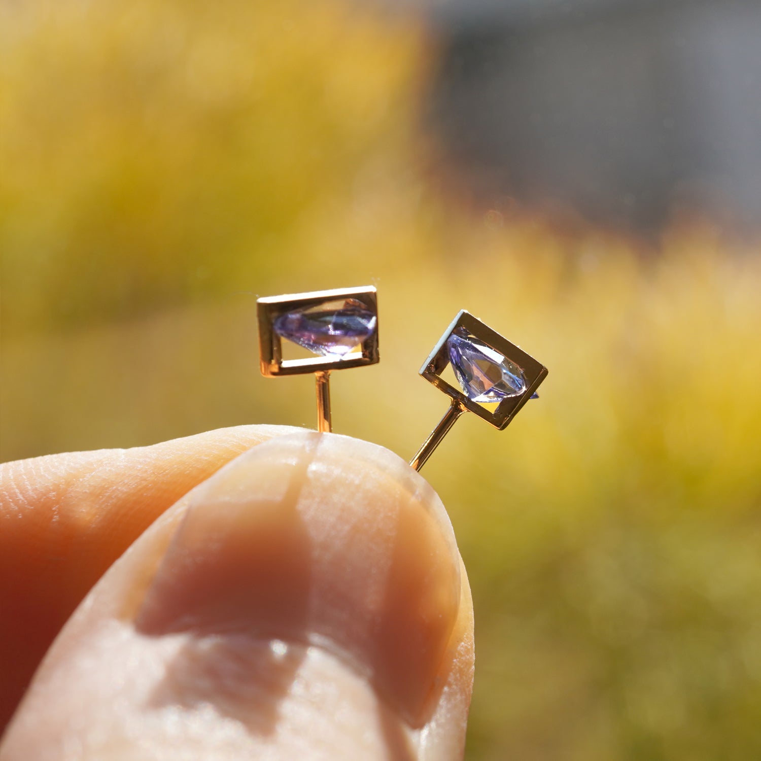 タンザナイトの青紫の色味とカット面が際立つK10イエローゴールドピアスのサイドから見たクローズアップ（ペア・ポストK18YG）